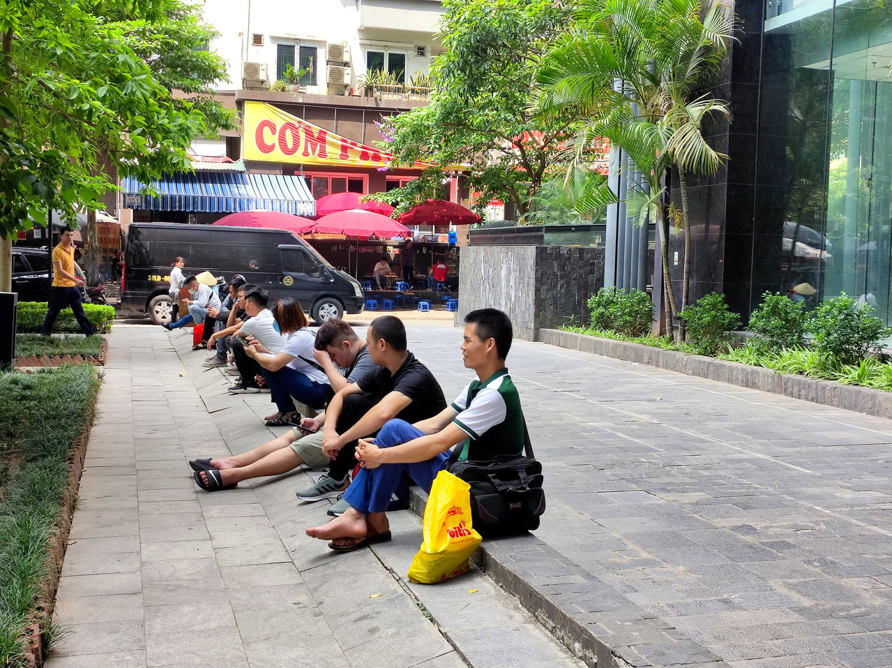 越南首都河内市高温连续多日飙破摄氏40度，图为19日在驻越南代表处楼下广场等待洽公的民众，当中不乏穿著拖鞋、凉鞋与短裤的民众。图／中央社记