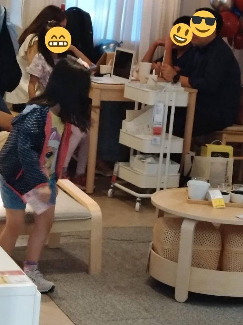 兩位成年人和兩名小朋友坐在櫈上，枱面有食物和飲料，旁邊傢俬掛上價錢牌，明顯是一間傢俬舖。（facebook群組「香港交通及突發事故報料區」圖片）
