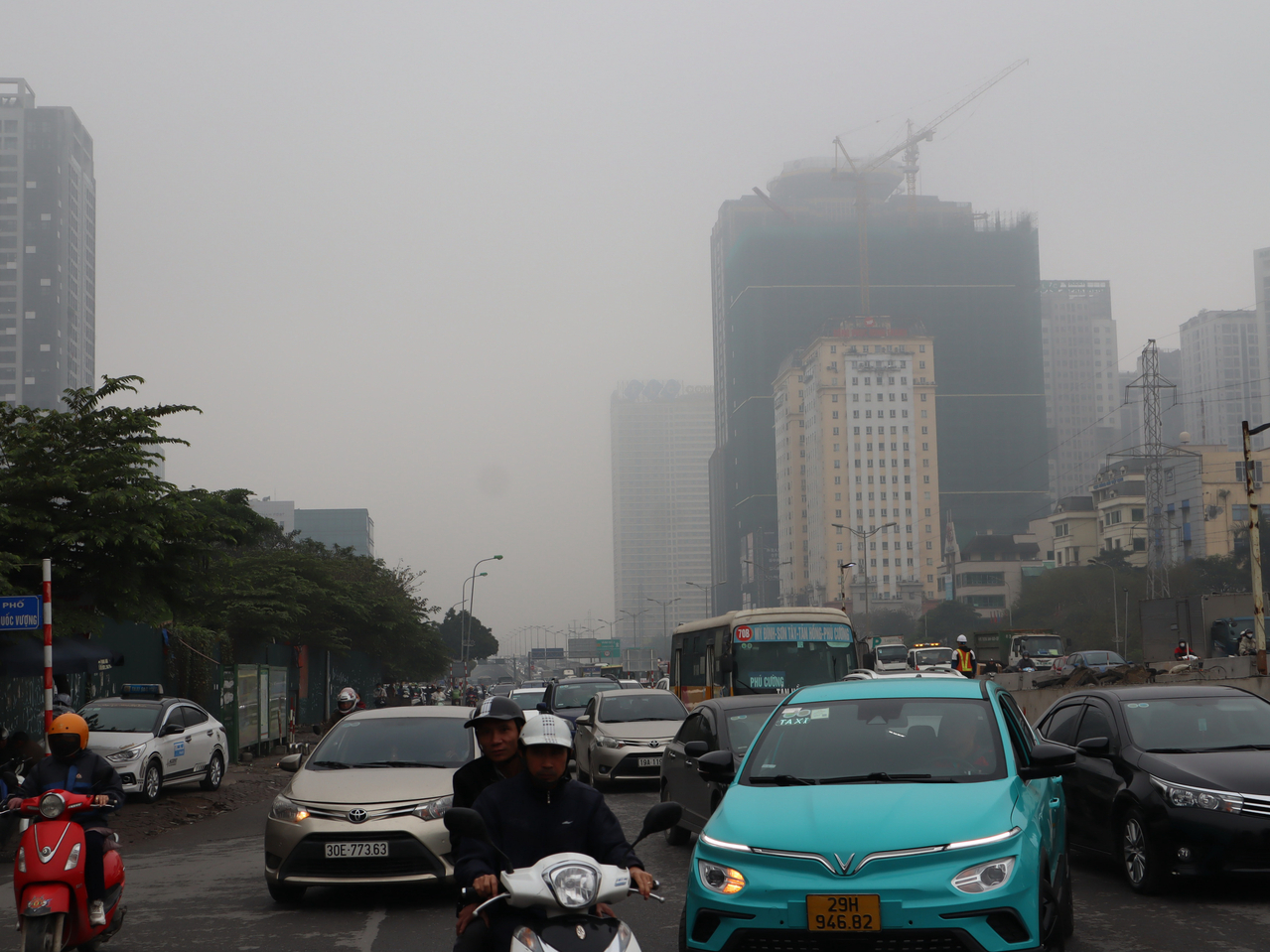 越南首都河内市共有650多万辆摩托车，被视为主要的空气污染源之一。图摄于4日上午10时22分，汽机车驾驶们背后的天空一片灰蒙蒙，当时空气品质指标（AQI）逼近「非常不健康」程度。中央社