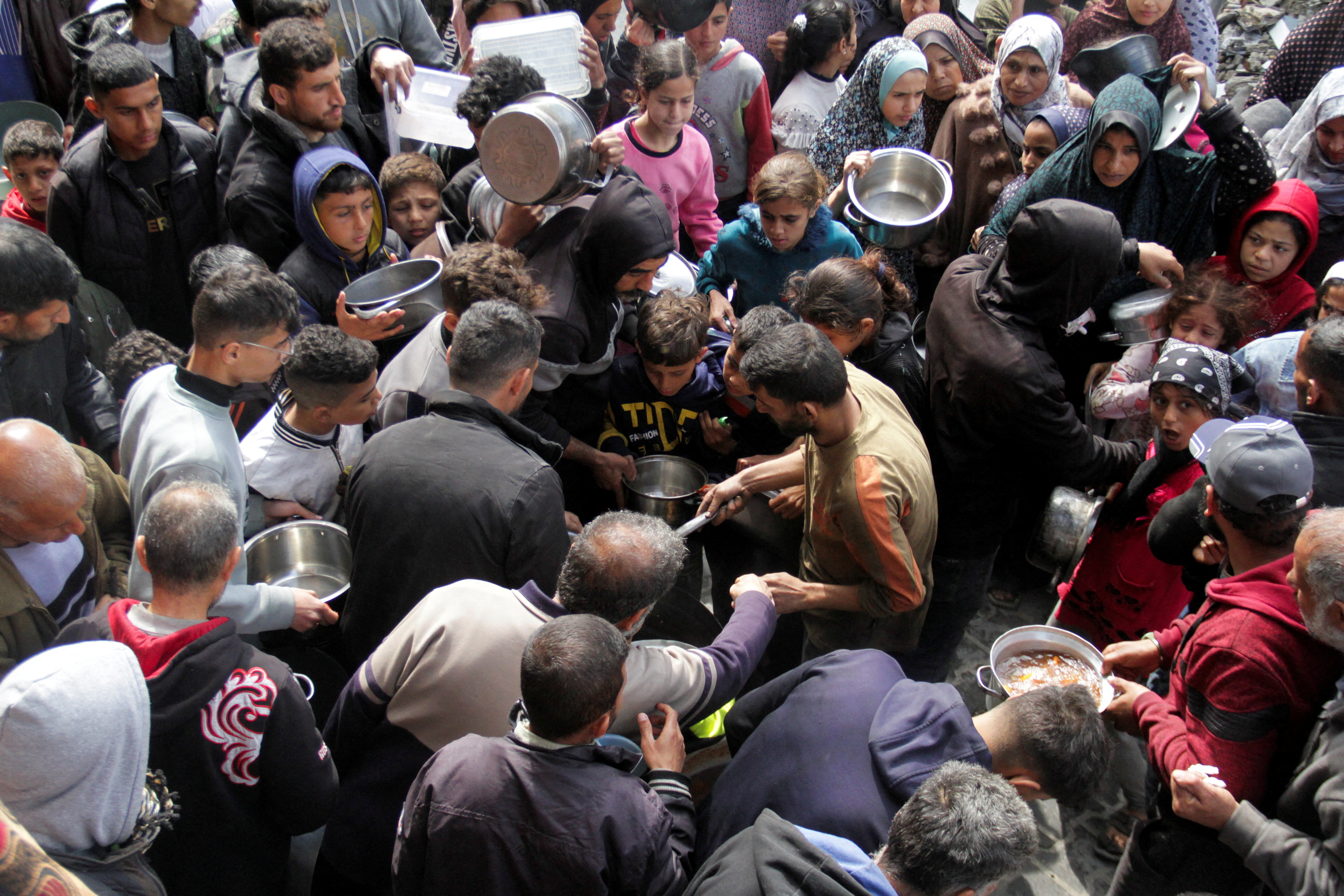 加萨北部贾巴利亚的巴勒斯坦人19日聚在一起准备领取免费食物。路透