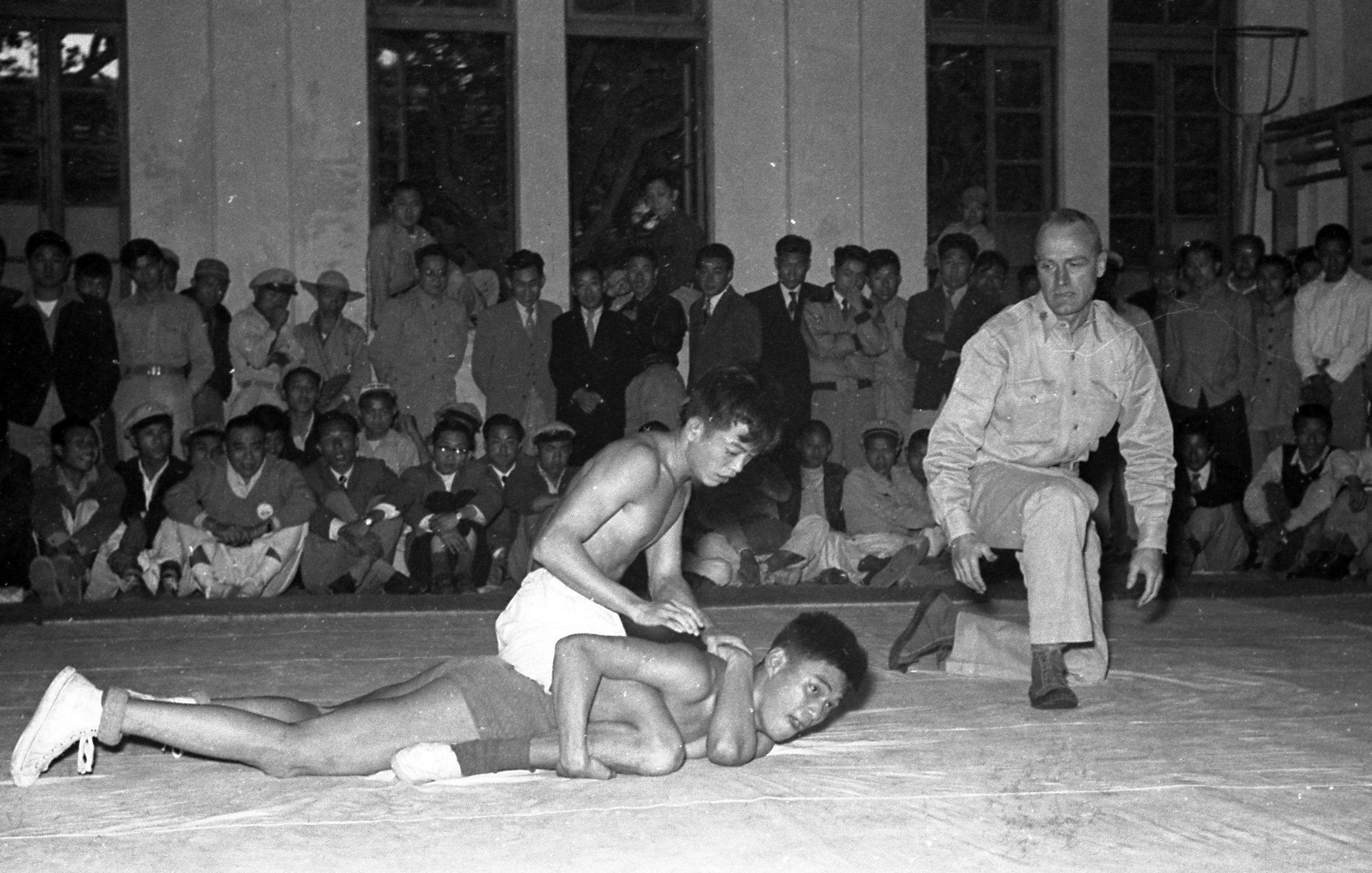 1954年3月31日，我国参加第二届亚洲运动会角力代表选拔，下午5时在师院体育馆举行，美军顾问团克林上校（前排右一）担任裁判。记者陈维在／摄影
