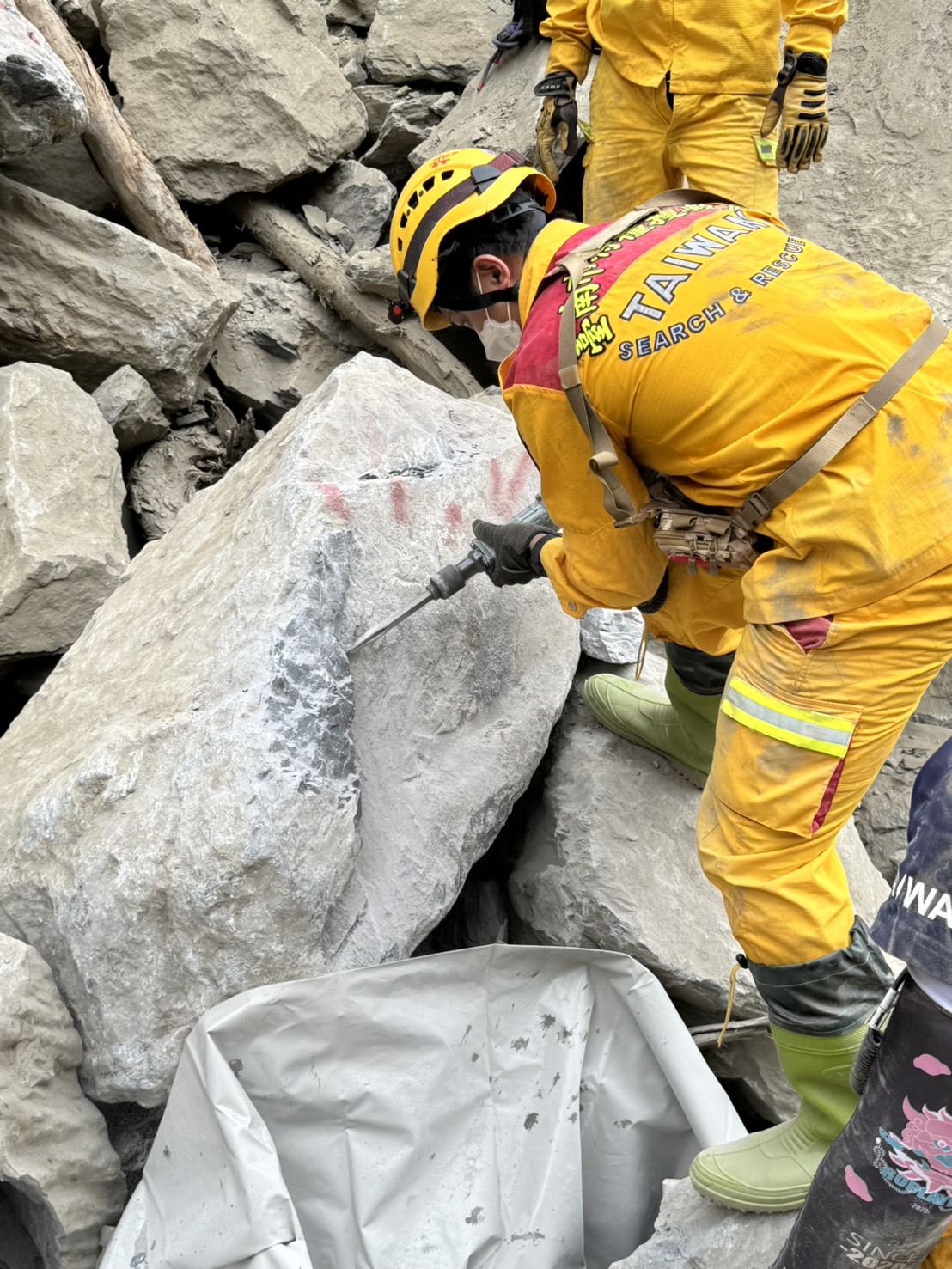 搜救人员上午9时25分在砂卡礑溪河床上巨石堆中发现2人被埋土石中，明显死亡，身分待确认。图／花莲县政府提供