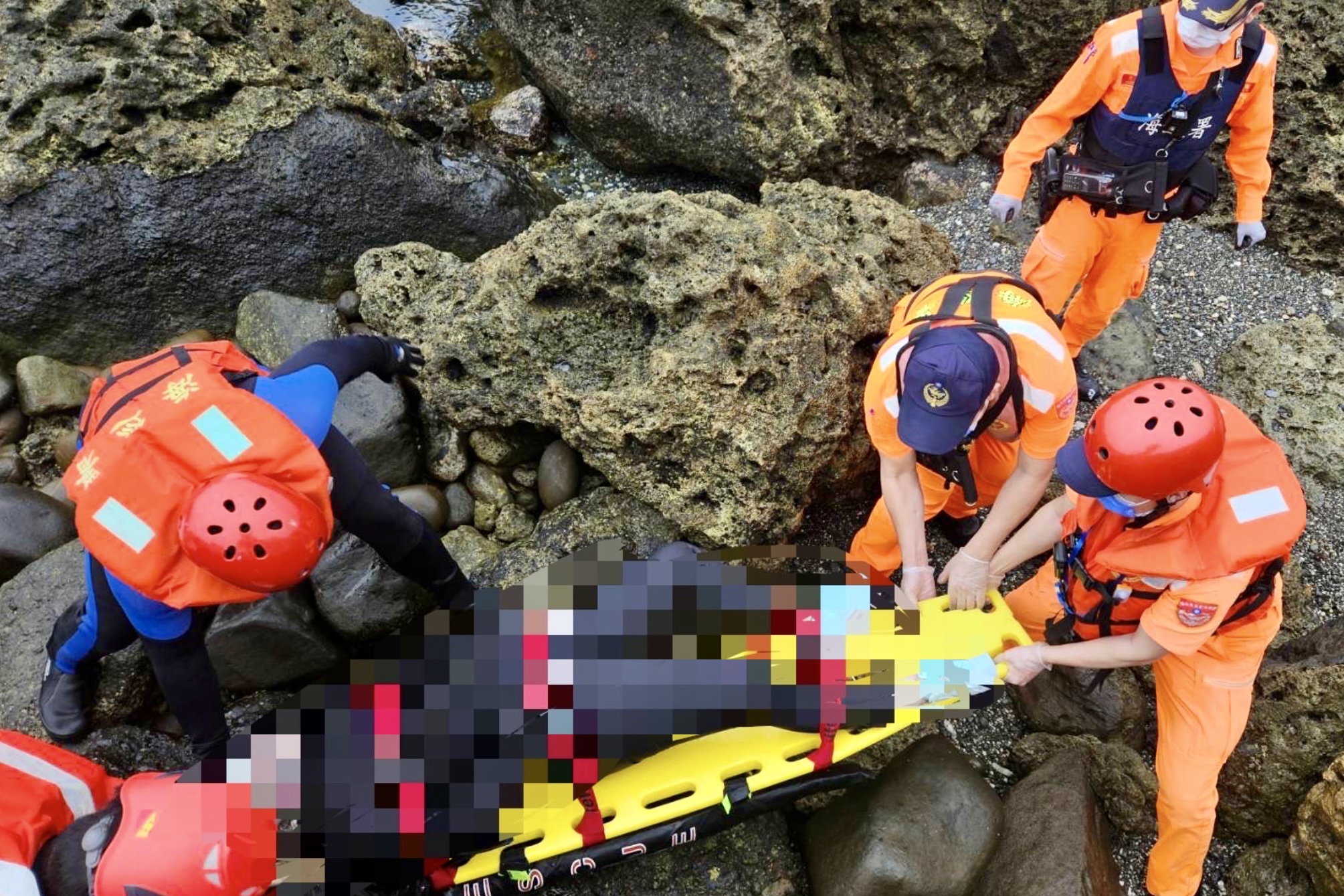 海巡人员将石梯坪游憩区南侧礁岩处的女性浮尸拖回岸上。记者古和纯／翻摄