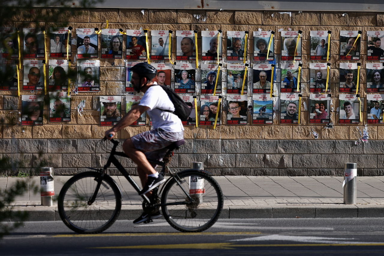 民众6日骑单车经过以色列特拉维夫一幅挂有一批被哈玛斯掳走人质照片的墙。路透社