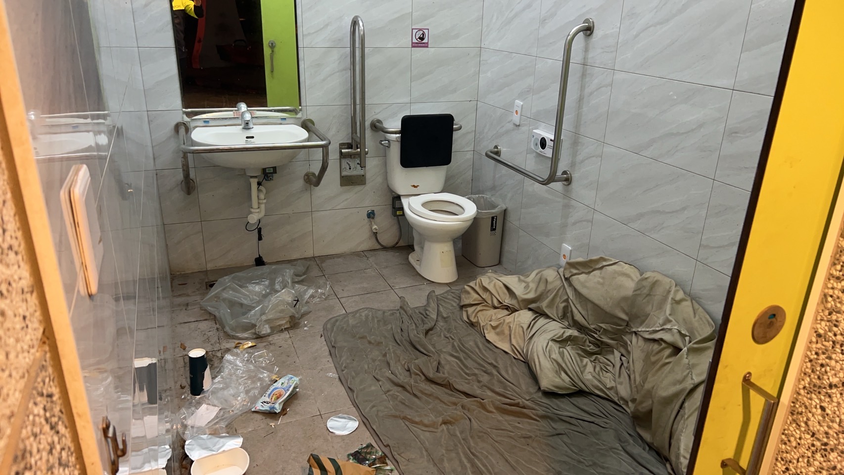 新竹县竹北市豆子埔公园残障厕所内有棉被、生活用品和吃完食物，且门遭反锁，疑似有街友长期占住。图／民众提供