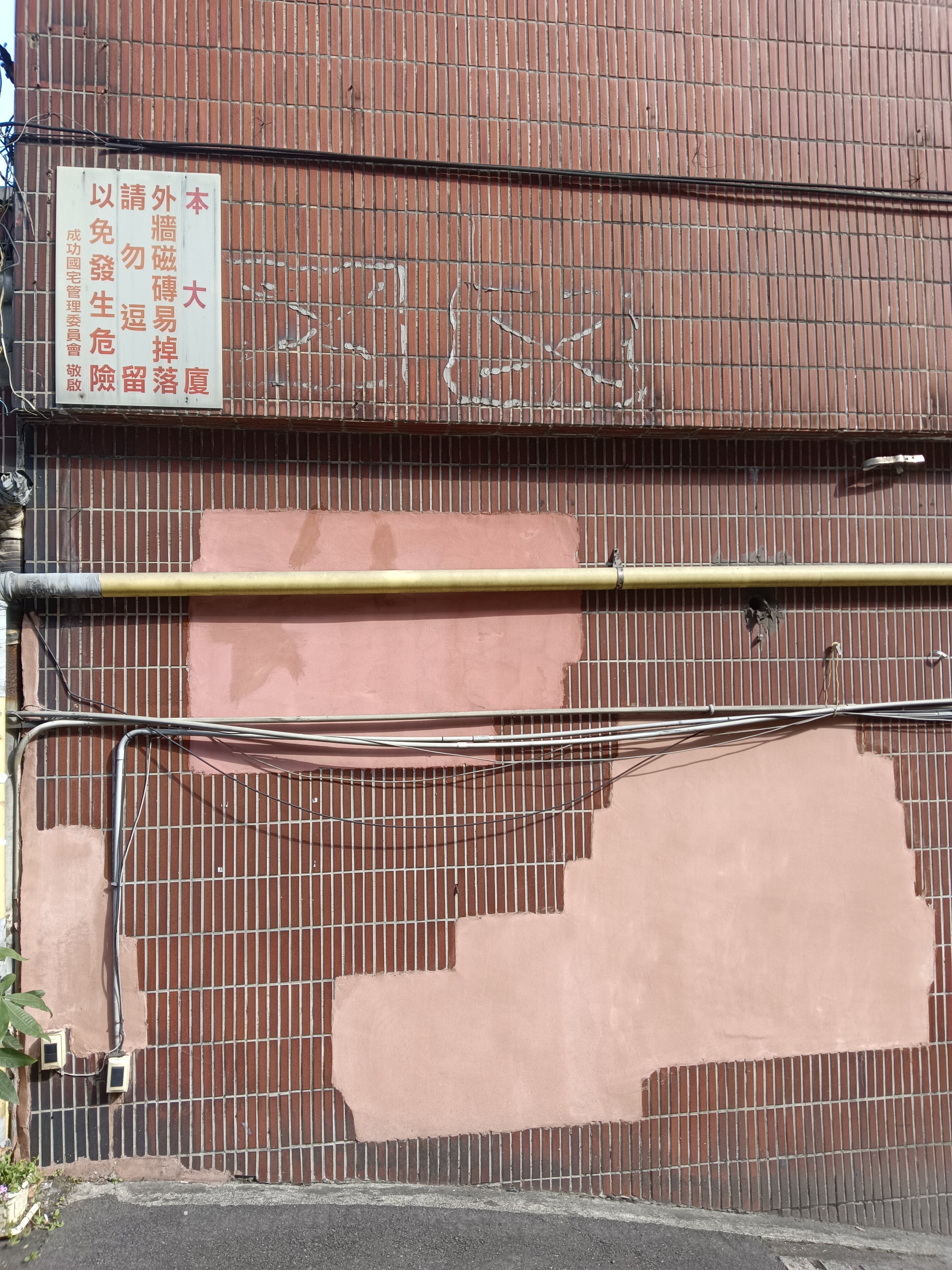 基隆市成功国宅社区外墙多处磁砖剥落后，事后涂抹弹性水泥补救，东一块、西一块如「癞痢头」。记者邱瑞杰／摄影