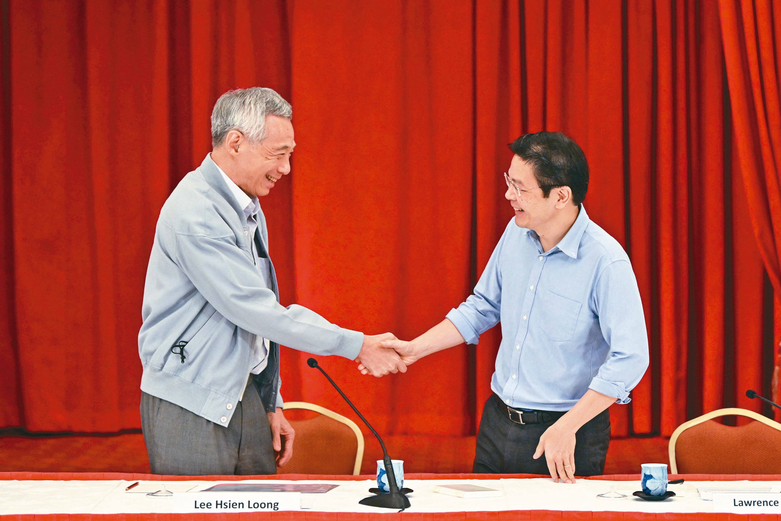 新加坡总理李显龙（左）2022年在一场记者会后与财长黄循财（右）握手。李显龙15日宣布将卸任，由副总理黄循财接任总理。（路透）