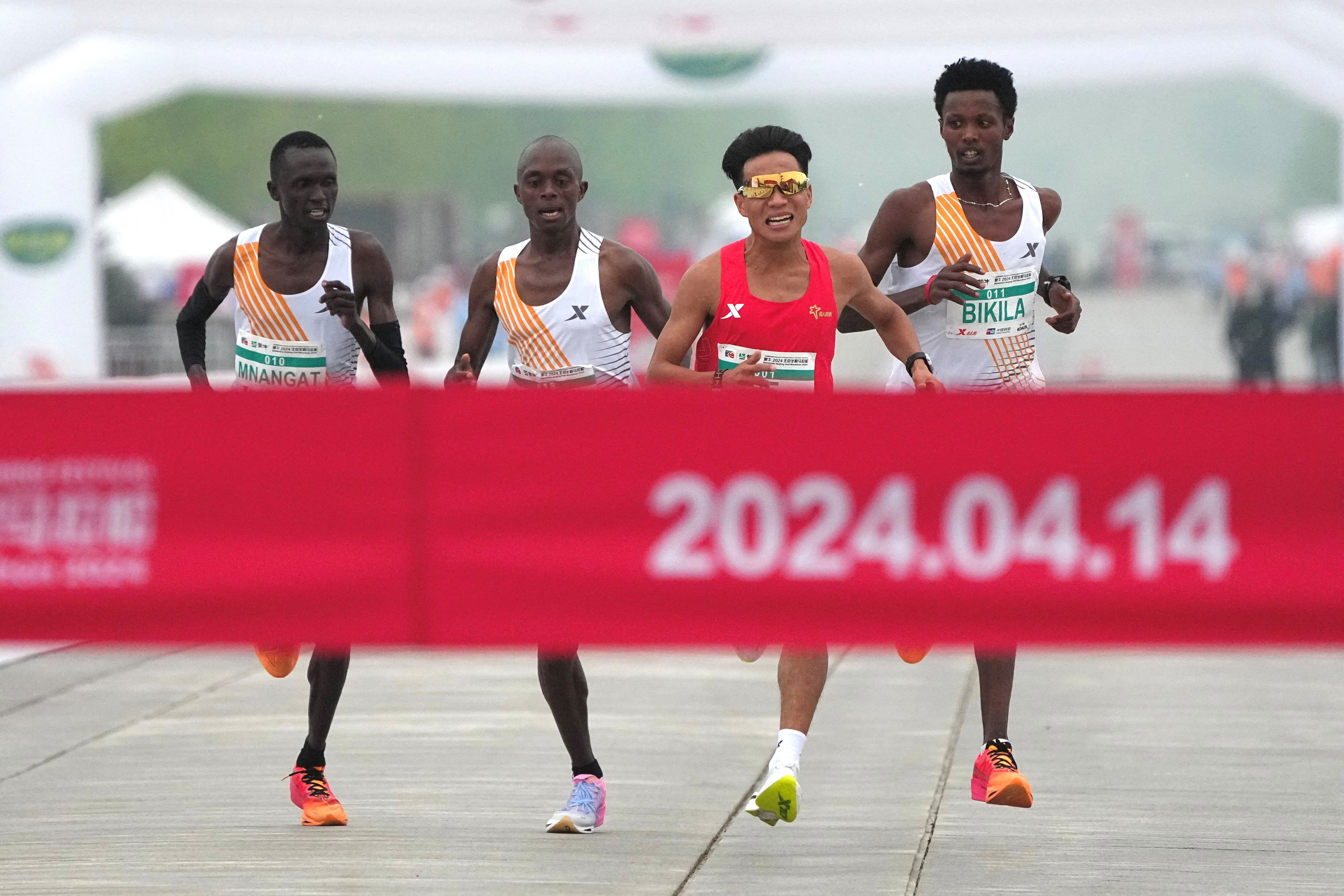 北京14日举行半程马拉松爆出跑假赛争议，3名领先非洲选手最后关头疑似护送何杰（右二）率先冲线，遭网友讽刺半马变「伴马」，事后一名非洲选手受访自招只是陪跑员。路透
