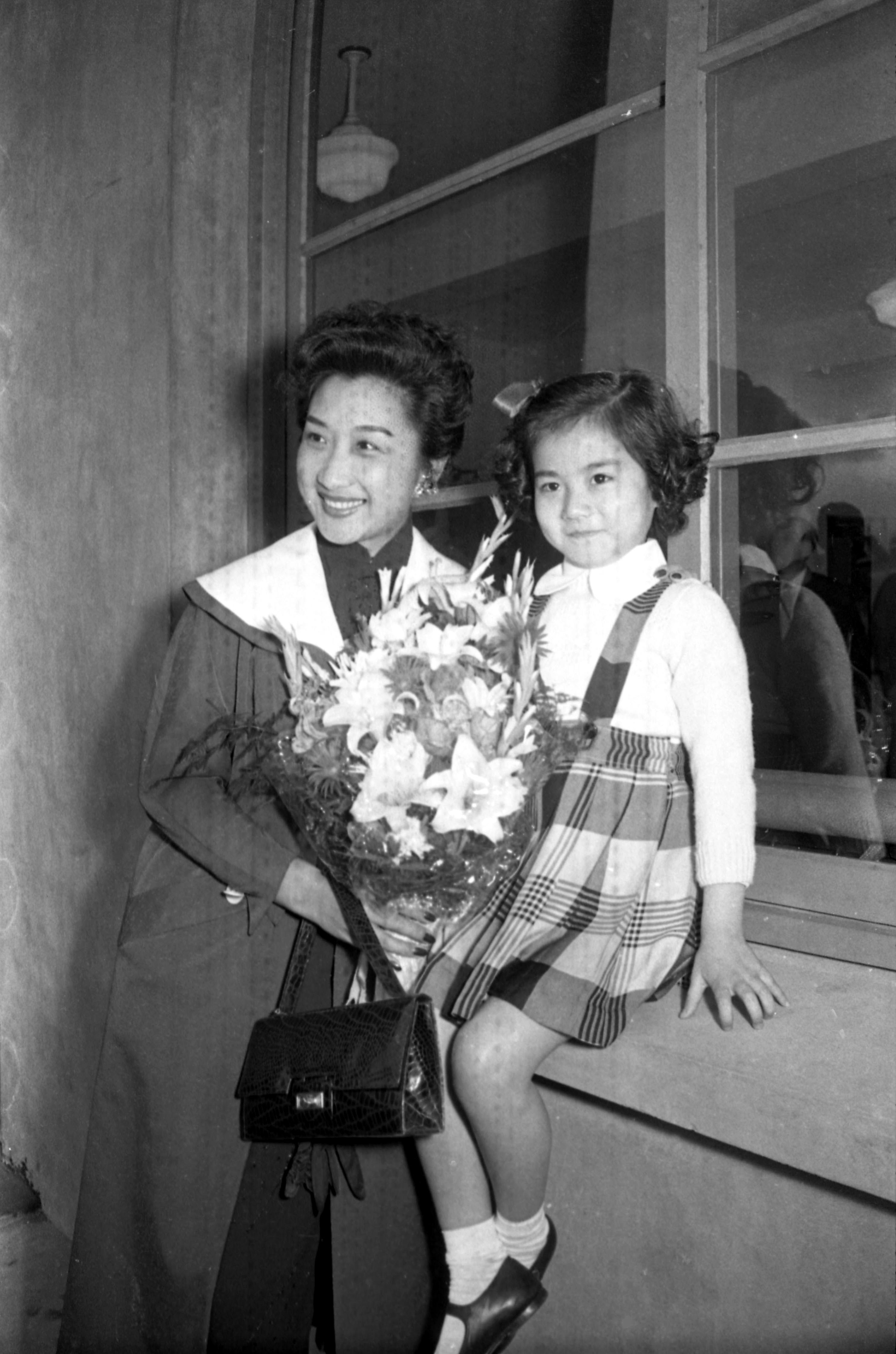 1955年4月24日，应邀拍摄「圣女妈祖传」担任女主角的影星周曼华（左），由香港飞抵台北，在机场接受在妈祖片中饰演幼年时期妈祖的张小燕（右）献花。图／联合报系资料照片