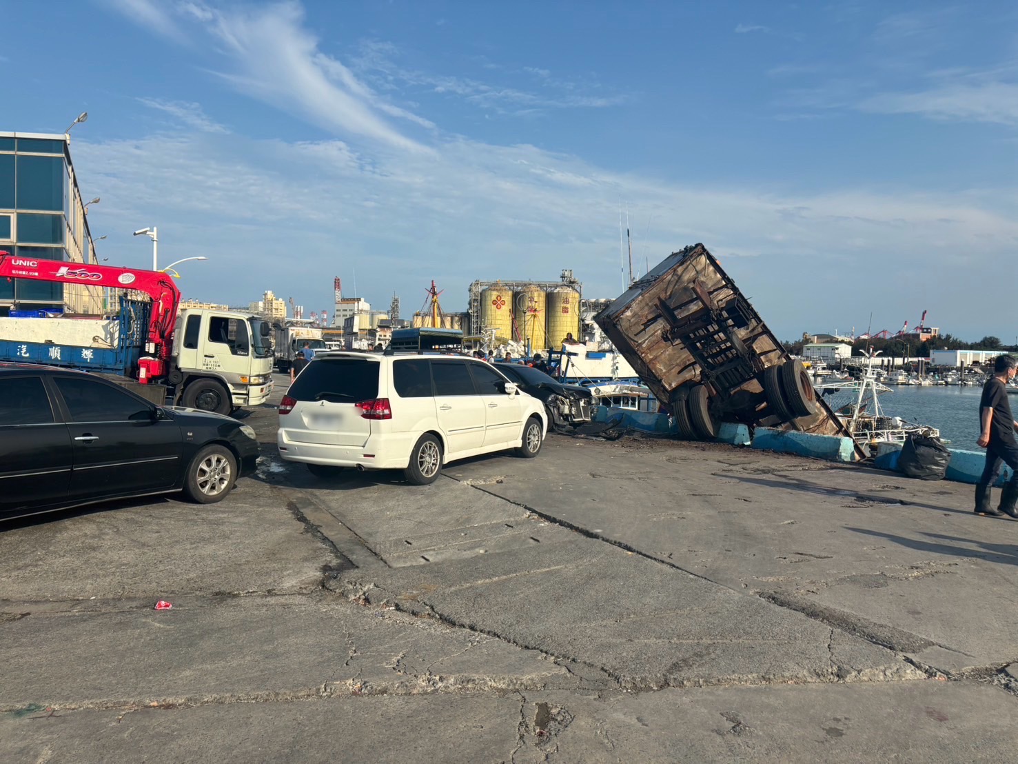 台中梧栖渔港南侧码头，惊传一辆报废大货车暴冲，撞向一旁2辆轿车，接著往海方向冲，悬在码头。图／民众提供
