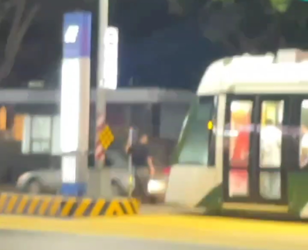 男子昨晚站在高雄轻轨高雄高工站的路口处，轻轨列车被迫停车。图／撷取自社会事新闻影音
