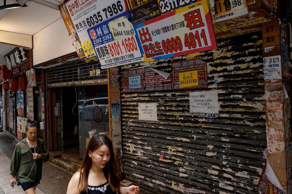 人们走过香港尖沙咀一家关闭的商店。路透