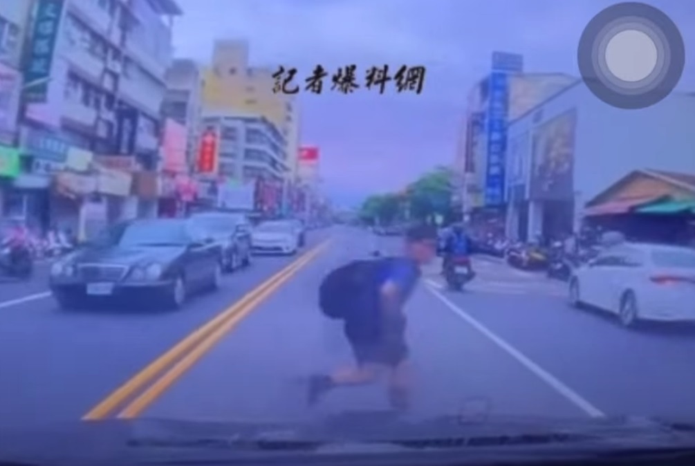 一名背著书包的男童，在马路对向车阵的缝隙中突然钻出，险些被撞。