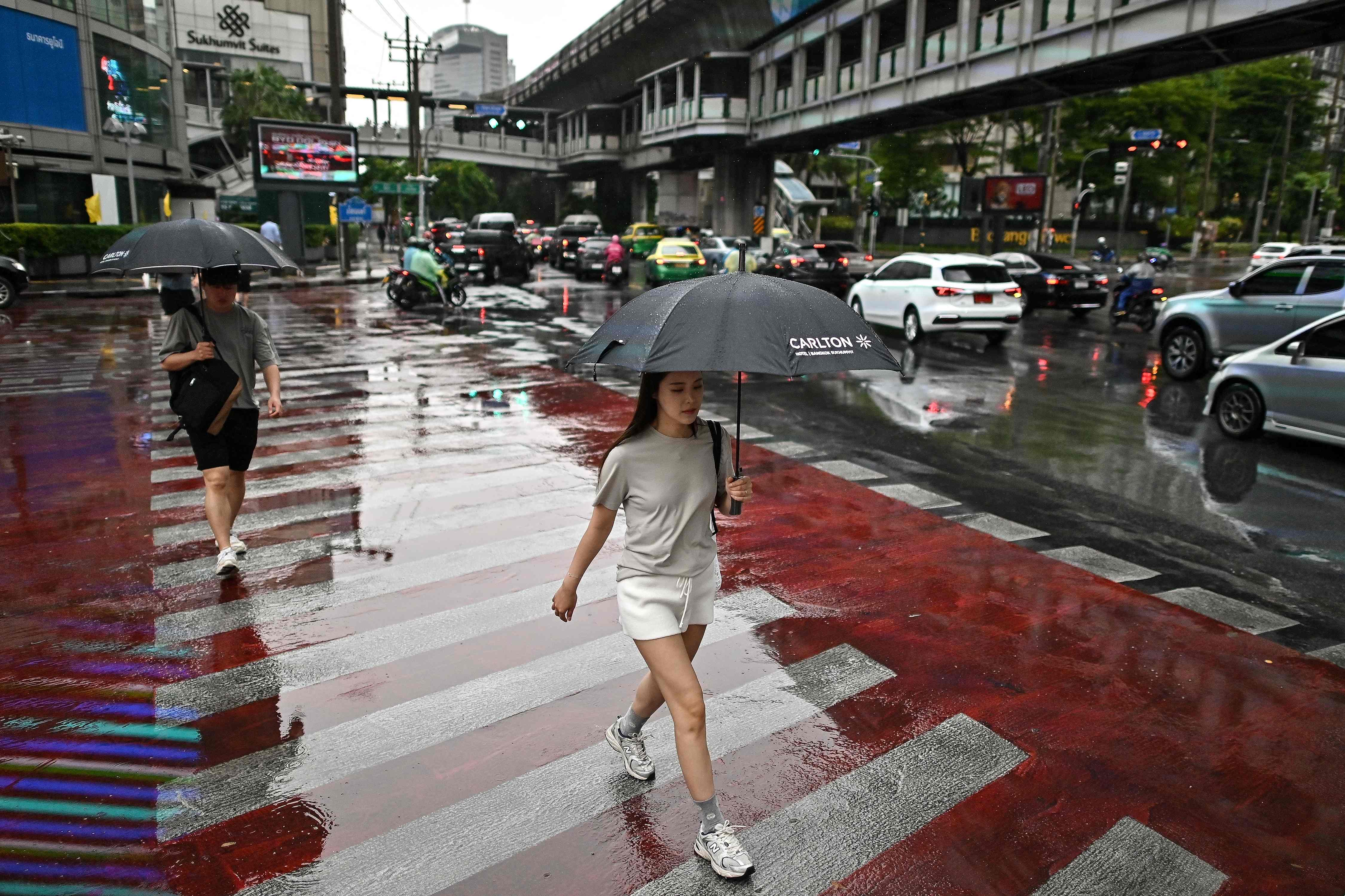 民众16日撑伞走过下雨的泰国曼谷街头。图／法新社