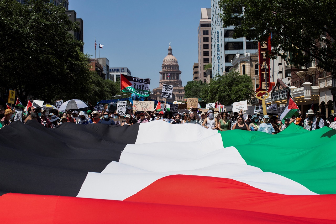 亲巴勒斯坦活动人士19日举著巨幅巴勒斯坦国旗，在美国德州首府奥斯汀的州议会外举行灾难日（Nakba）示威游行。路透