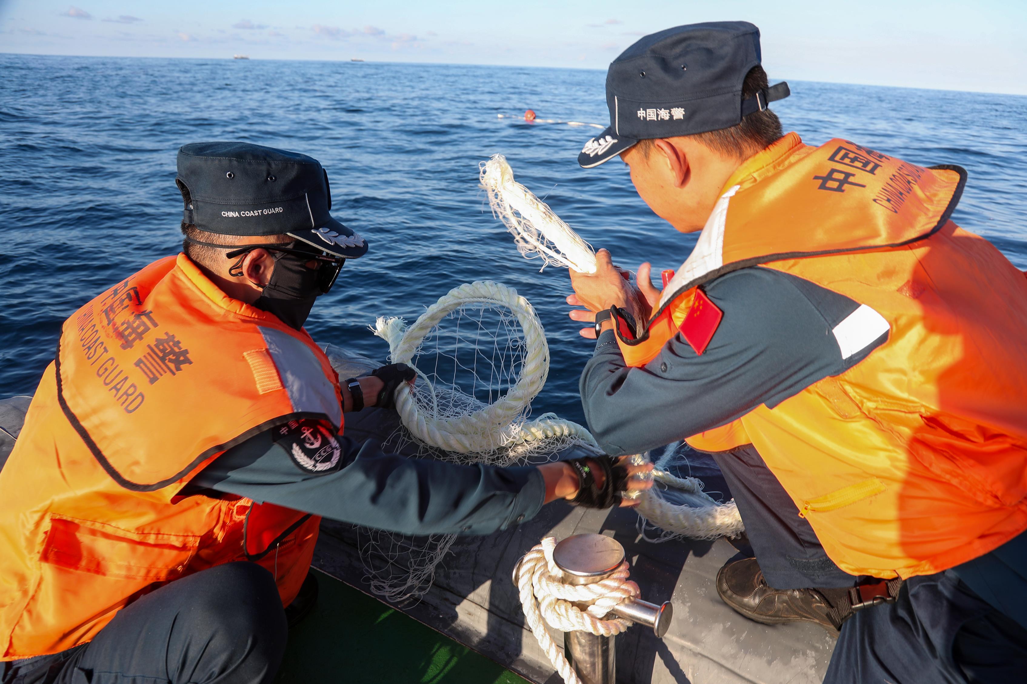新华社4日公布中国海警局赤瓜舰执法员在仁爱礁及其附近海域查看被菲方人员破坏的渔网。（新华社）