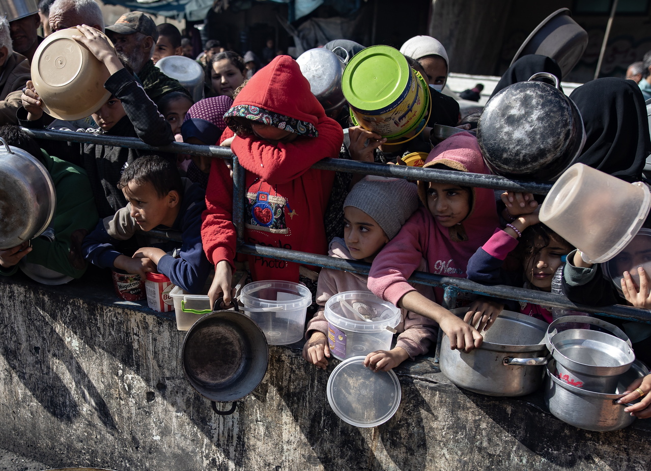 图为流离失所的巴勒斯坦儿童，在加萨走廊南部拉法难民营等待领取食物。(欧新社)