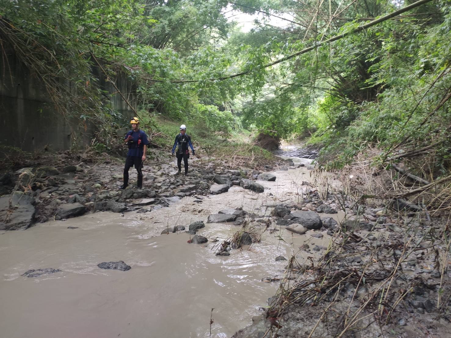 搜救人员沿著泥泞的河道搜寻农妇。图／高雄市消防局提供