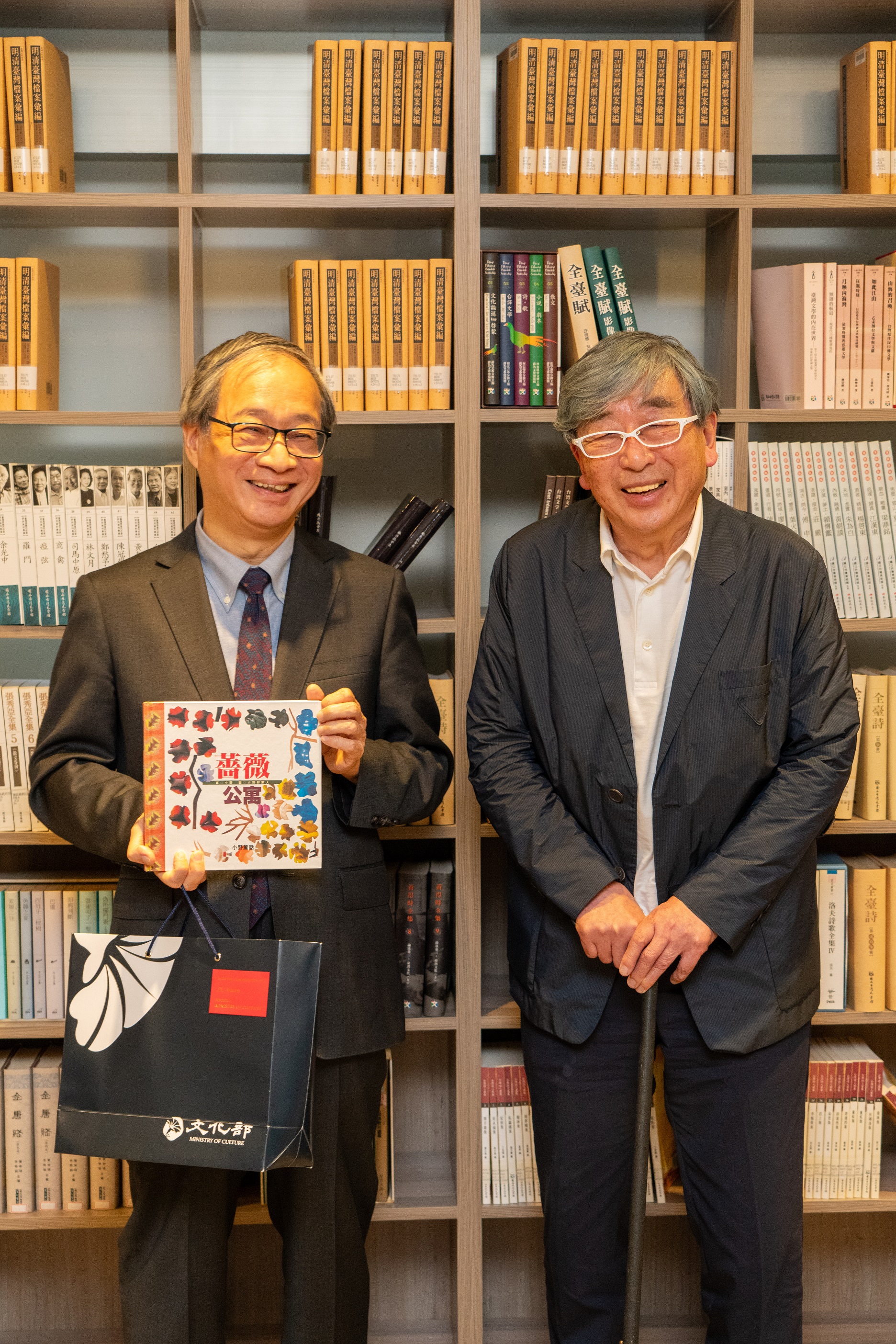 文化部长李远（左）选择自己的作品「蔷薇公寓」致赠建筑师伊东豊雄（右），该书用广告纸拼贴，借此表达对于环境、能源议题的关注。图／文化部提供