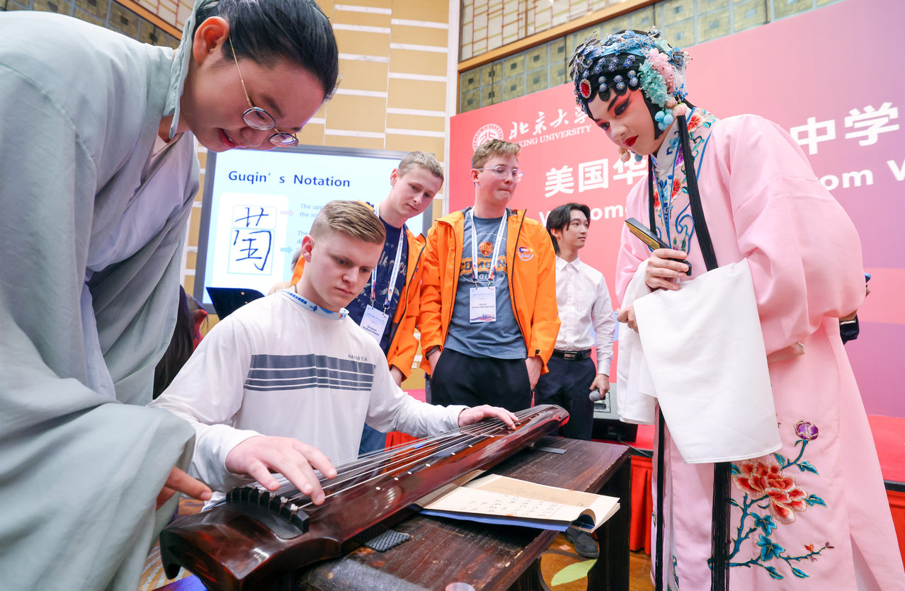 3月20日，在北京大学，中国学生在指导美国华盛顿州中学生代表团的成员弹奏古琴。（新华社）