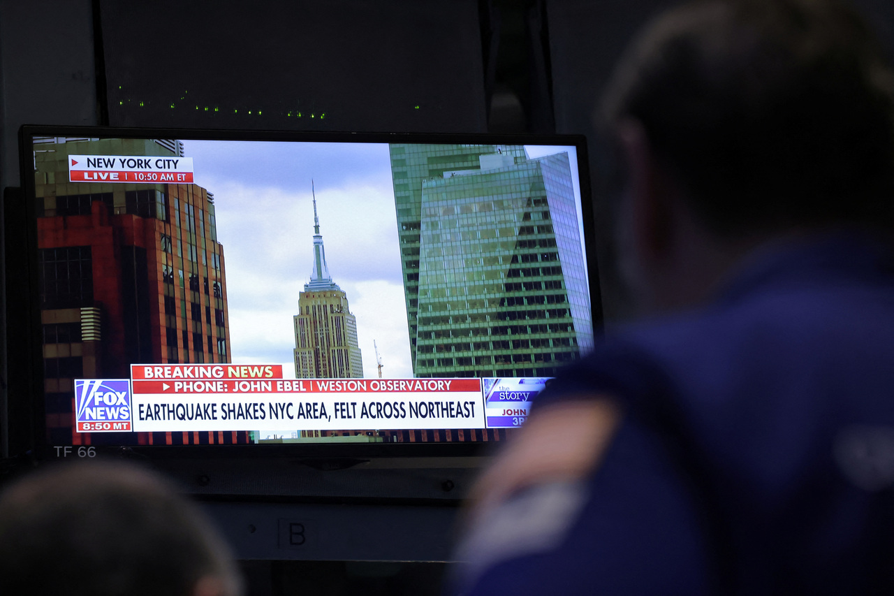 纽约证交所的电视萤幕不断出现地震的新闻快报。（路透）