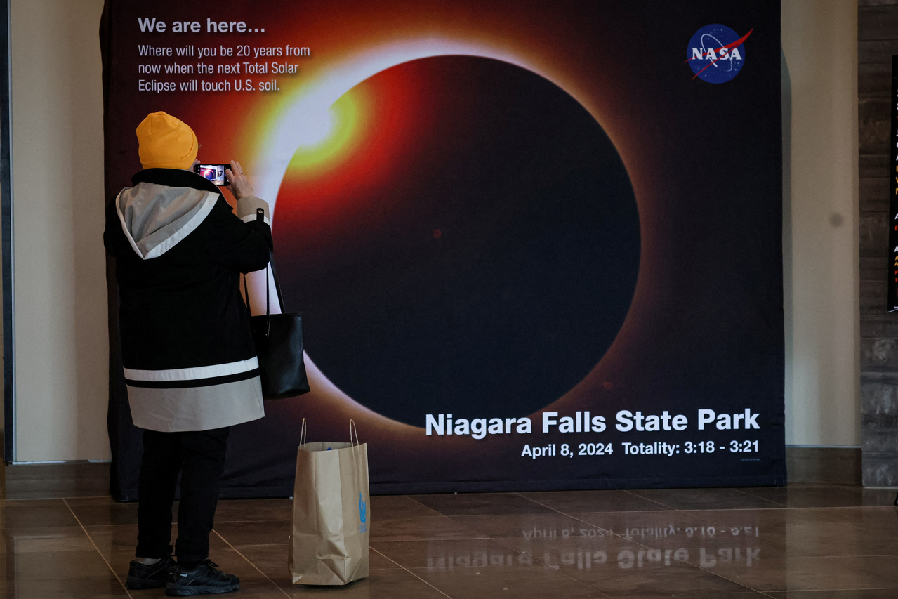 一名游客在尼加拉瀑布区拍摄NASA设置的日全食倒数展示牌。（欧新社）
