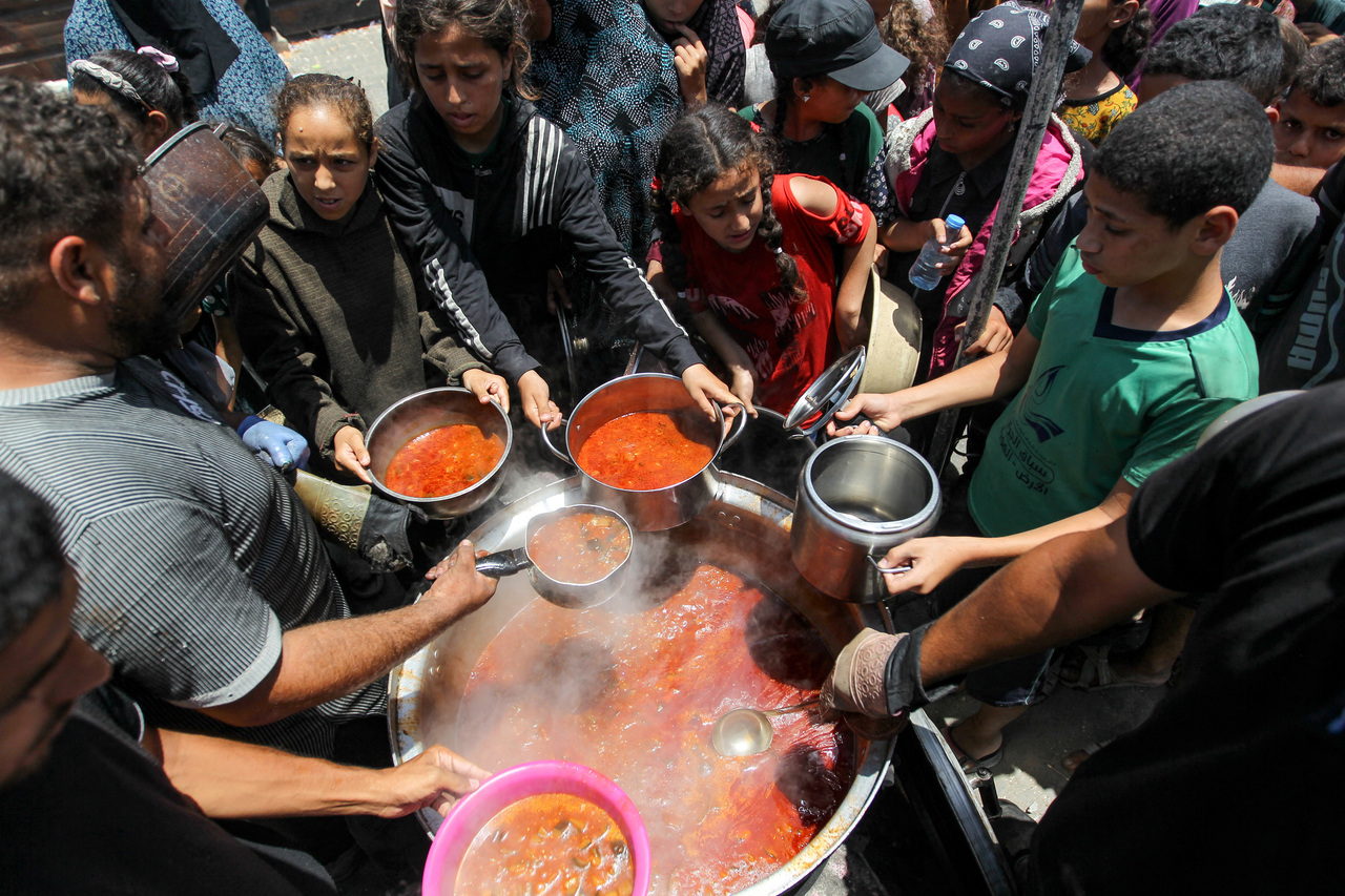 在加萨走廊南部的汗尤尼斯，由于以哈冲突仍持续，援助物资短缺，巴勒斯坦人19日聚集在一起接受慈善厨房烹制的食物。（路透）